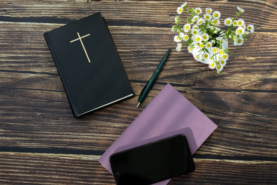 A Bible, a notebook and a pen on a wooden table