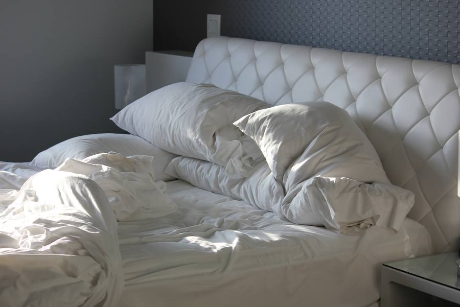 An unmade bed in dim morning light