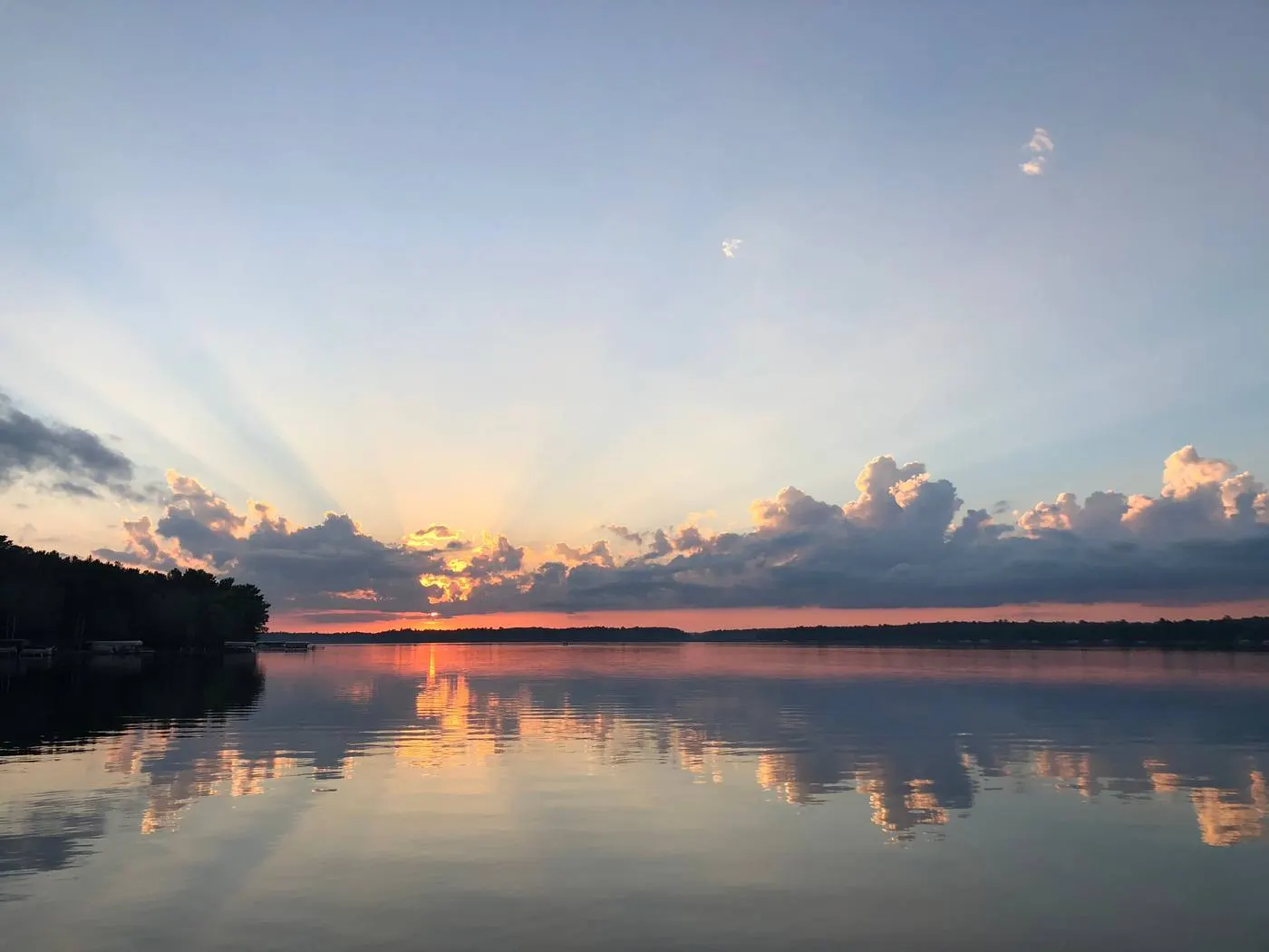Sunrise over a lake, rays fanning up through a low cloud bank